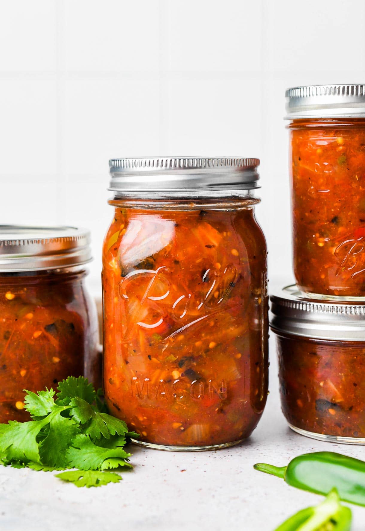 canned roasted salsa in ball mason jars, with cilantro next to it