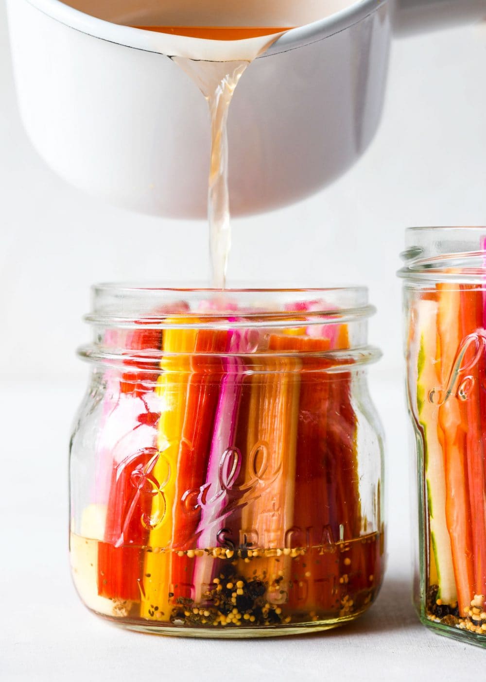 pouring brine into a ball jar that has swiss chard stems in it.