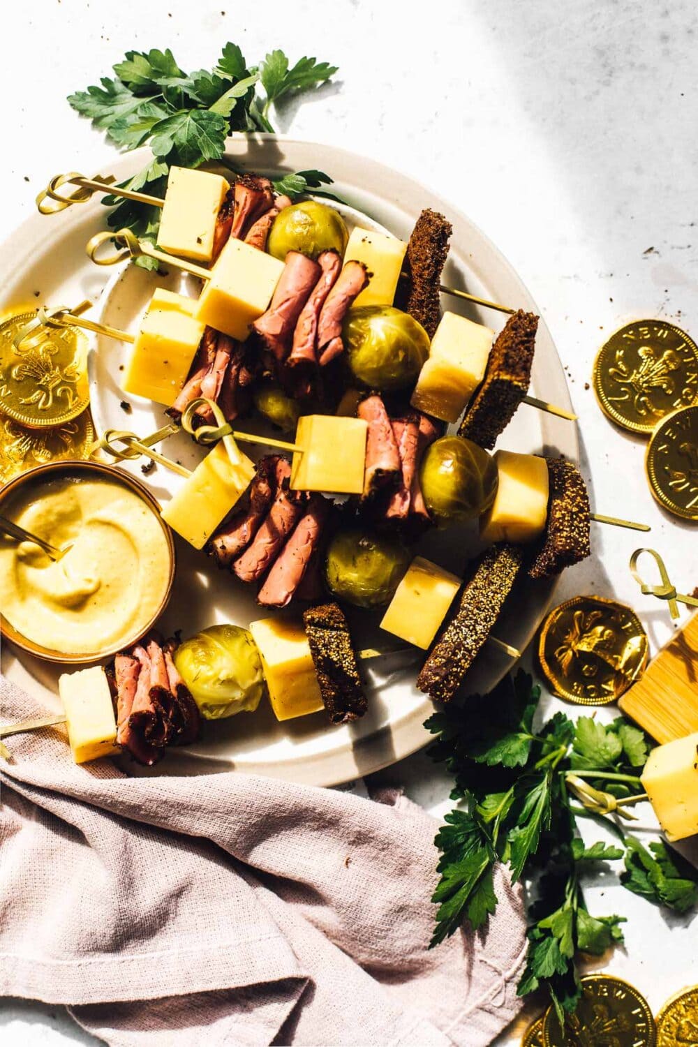 irish skewers on a plate with dijon mustard, gold coins to the right of plate