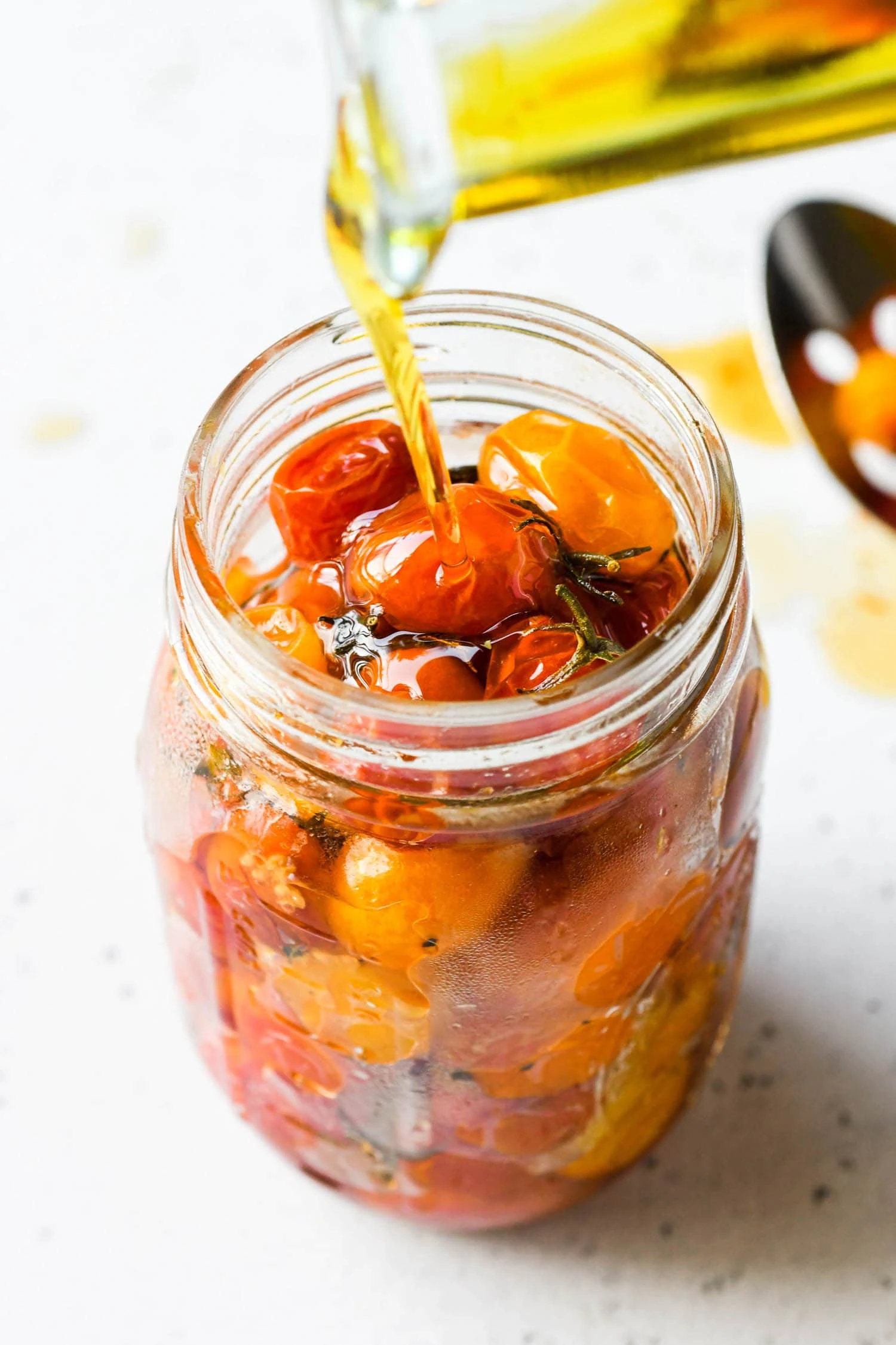 pouring olive oil onto cherry tomatoes