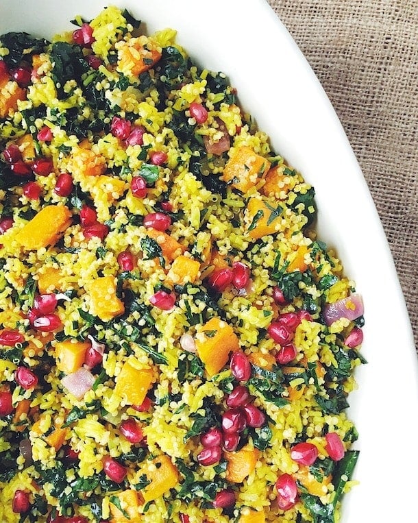 winter curry grain bowl with butternut squash and pomegranate seeds, served in a white bowl