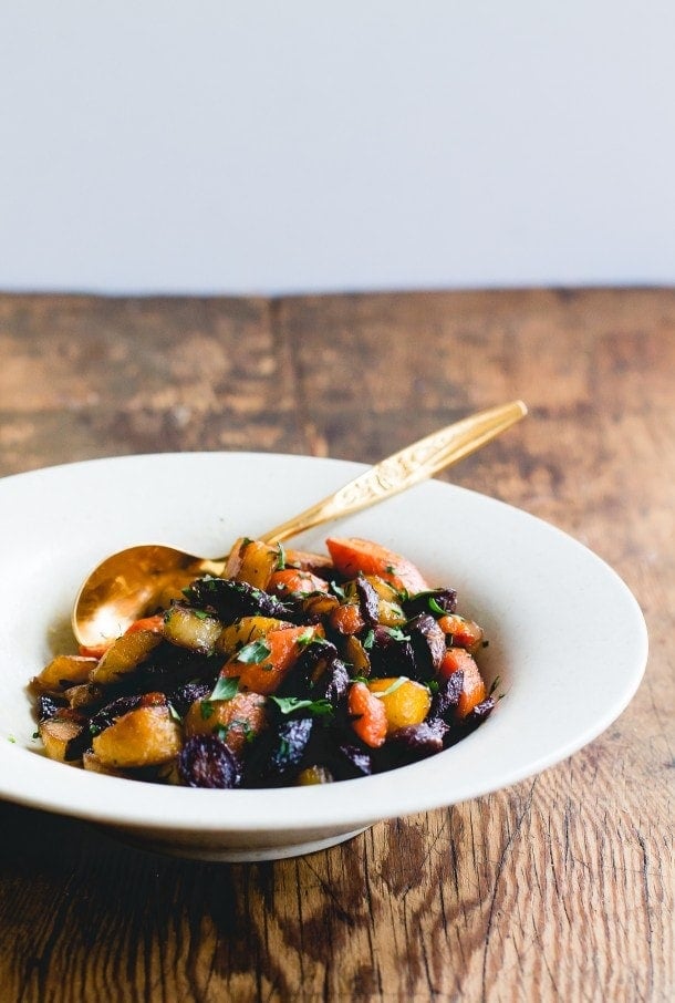 bowl of rainbow carrots with gold spoon.