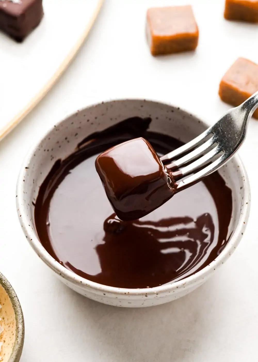 dipping caramels in chocolate, using a fork.