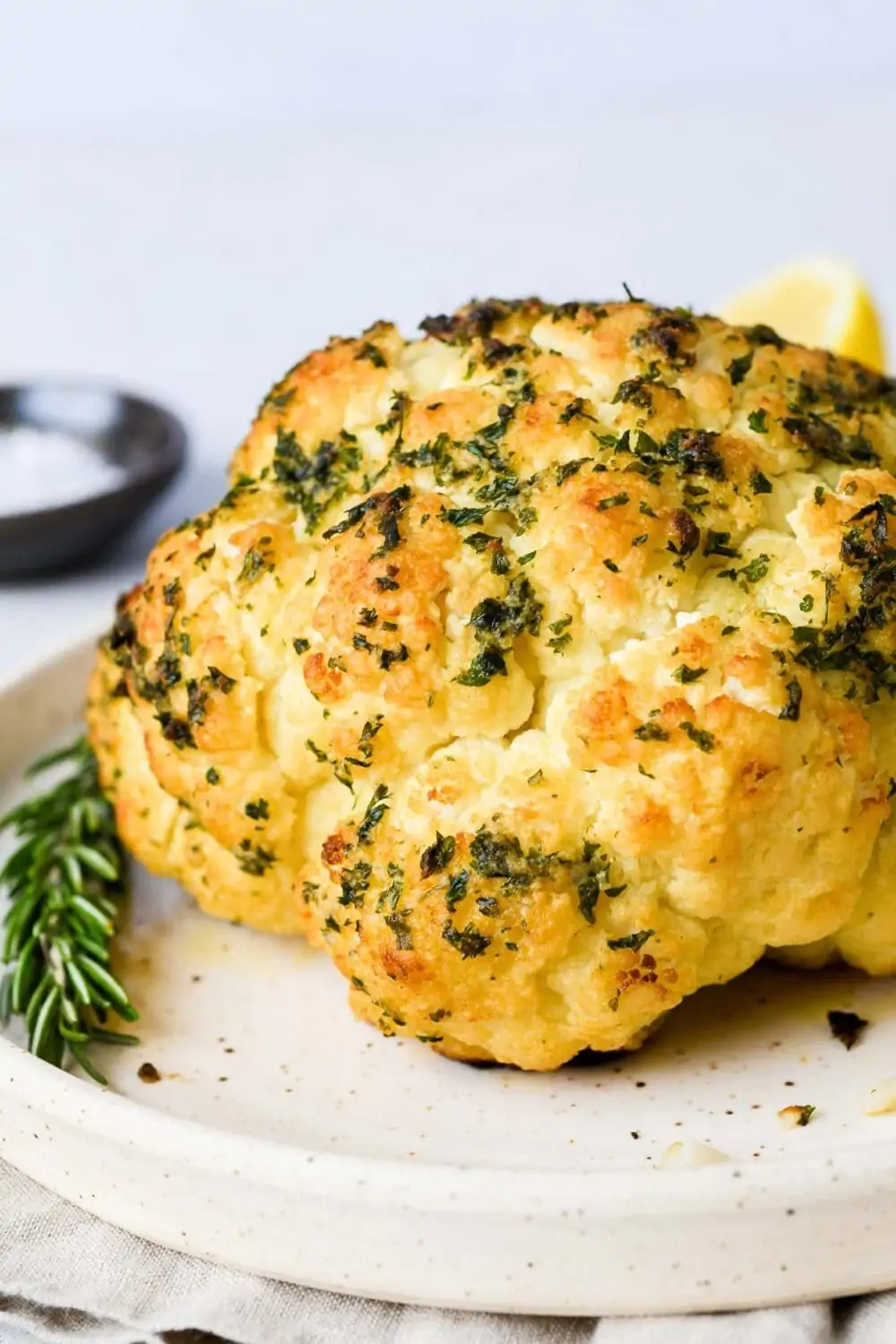 whole roasted cauliflower with herbs on a plate