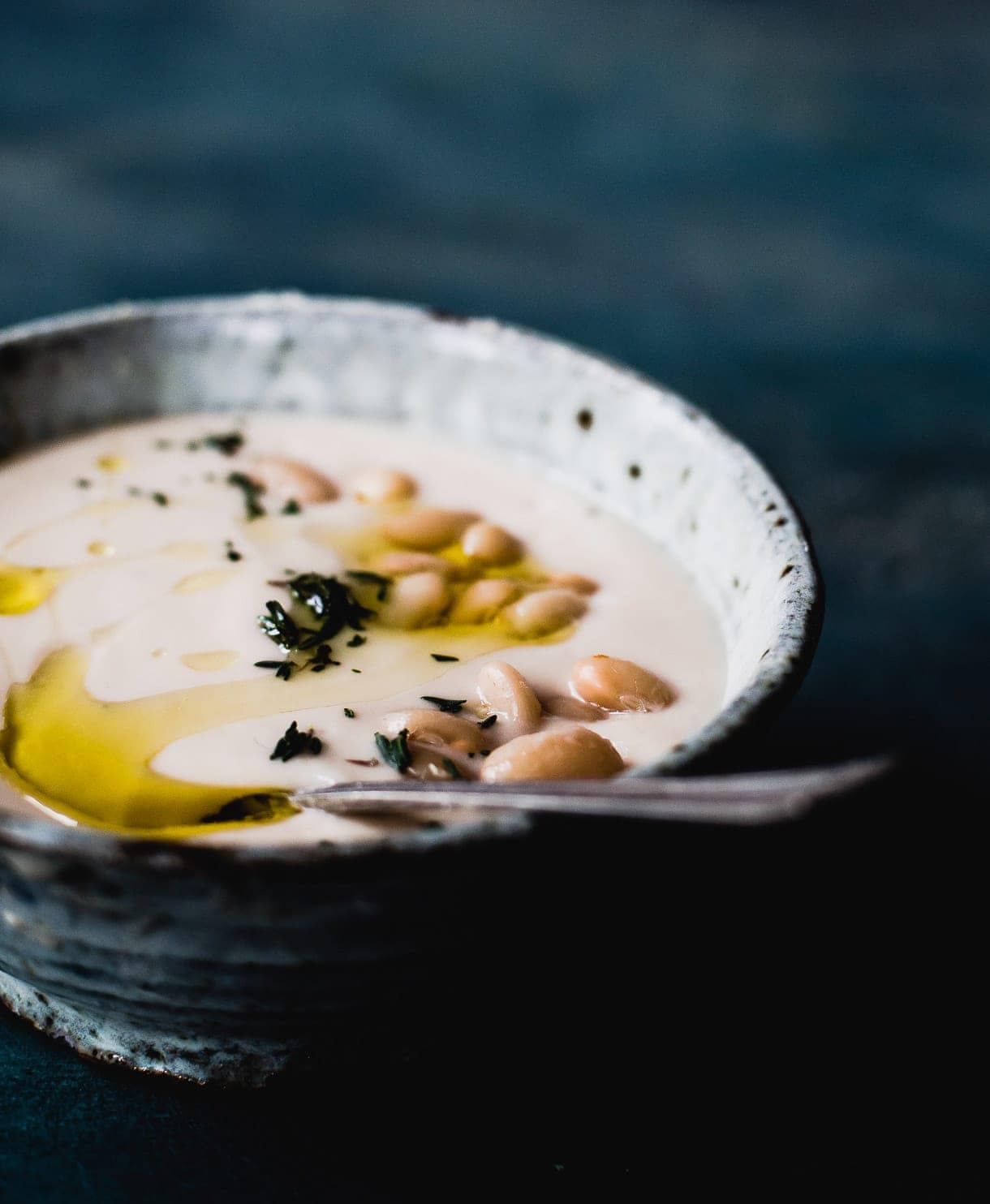 bowl of instant pot white bean soup with spoon and sprinkled on top with thyme