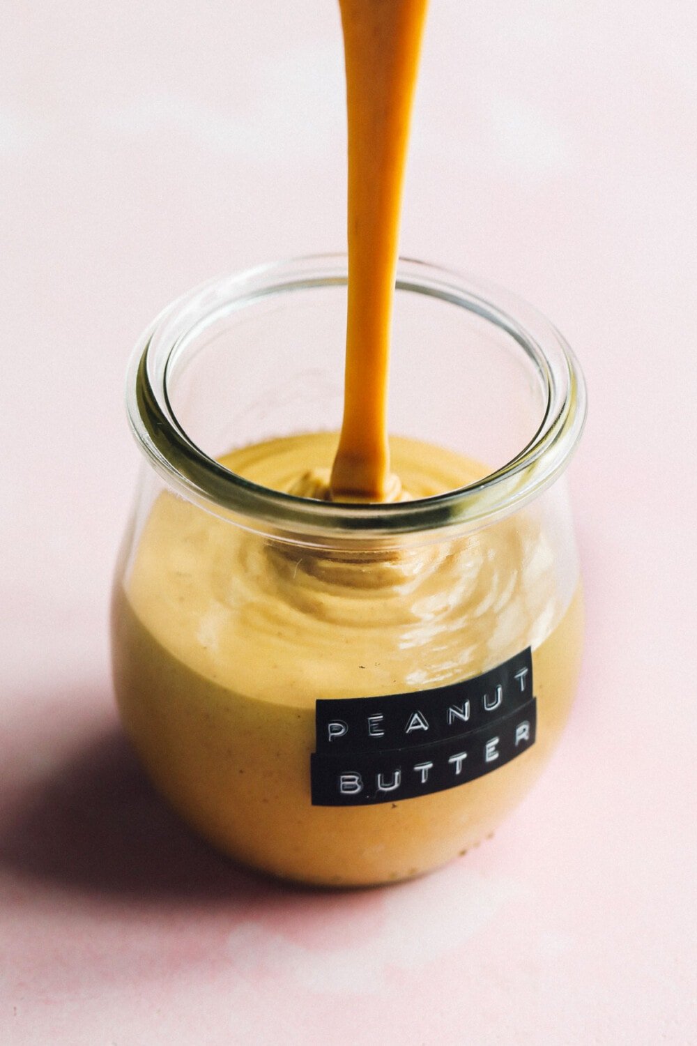 pouring peanut butter into a glass jar with label