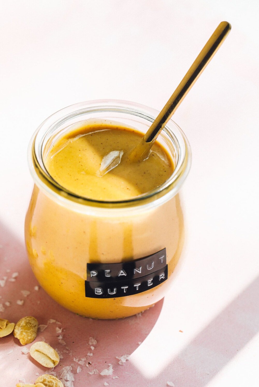 homemade peanut butter in glass jar with gold spoon