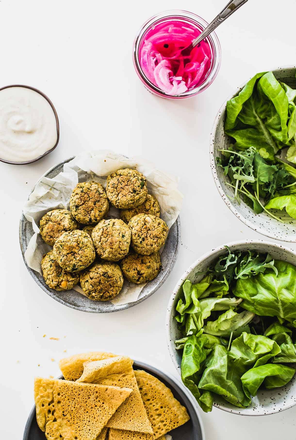 ingredients for making a baked falafel salad, everything nestled in bowls, overhead photo.