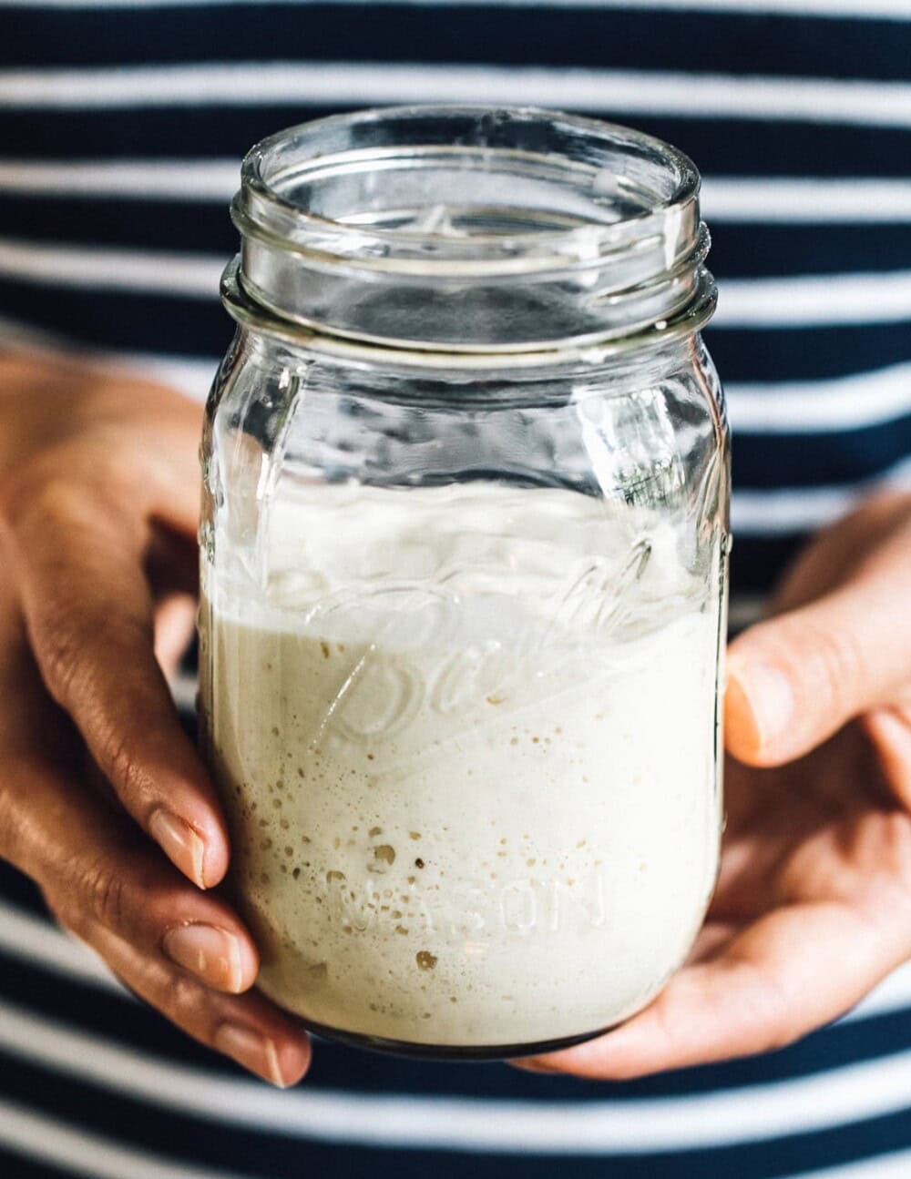 woman holding a jar of sourdough starter
