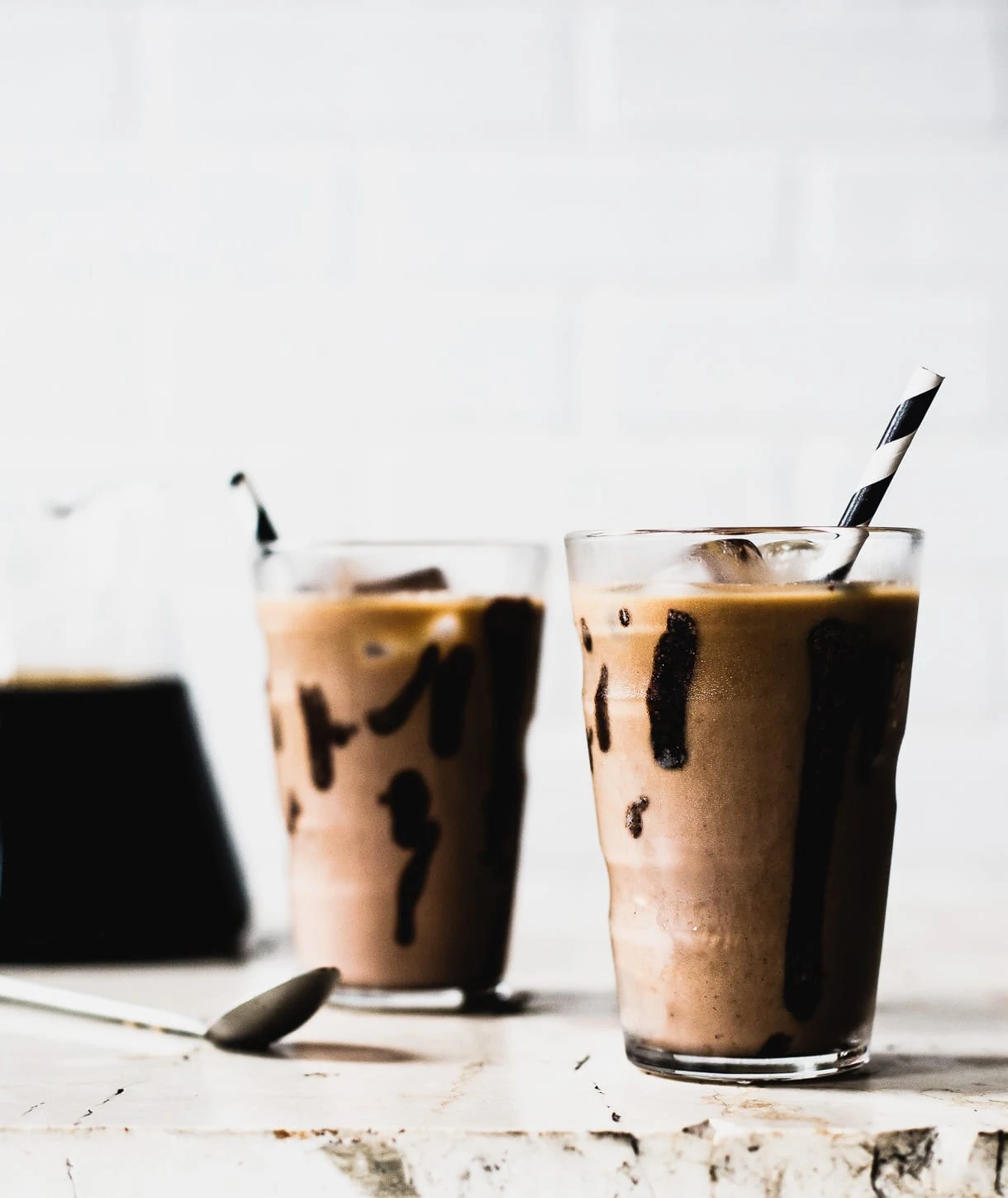 two glasses of iced mocha with black and white striped straws sticking out of them