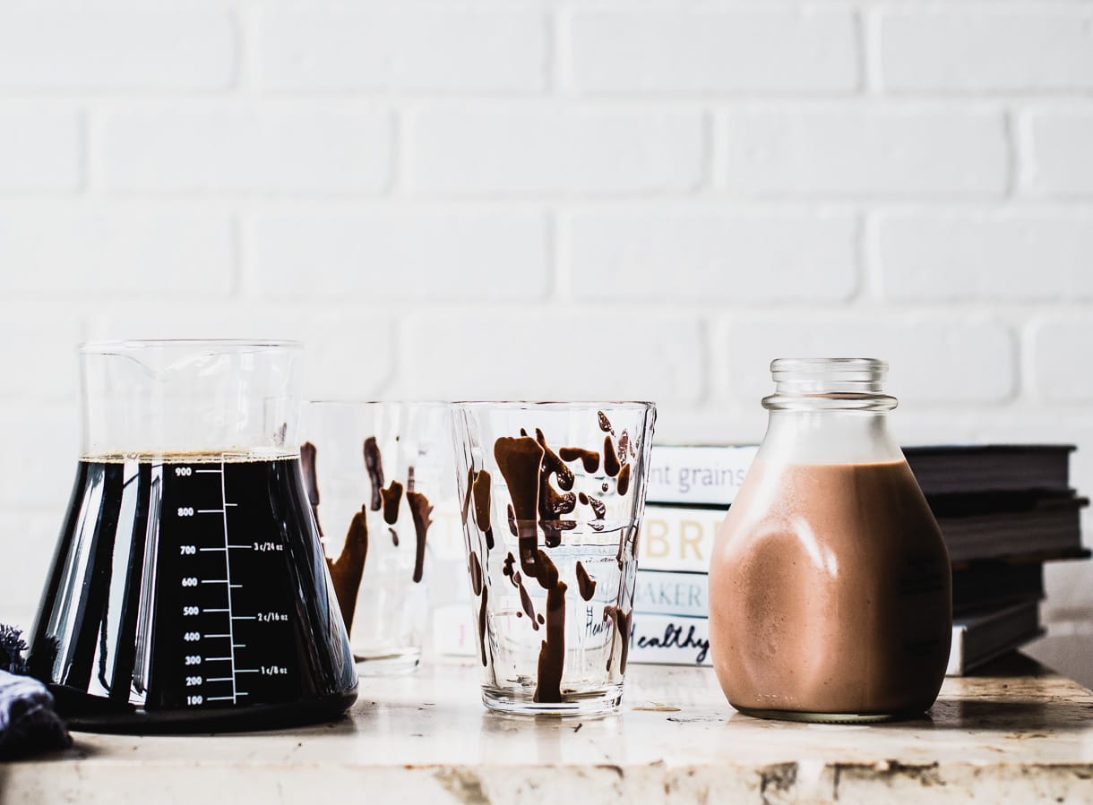 glasses with chocolate syrup swirled inside them, sitting next to cold brew coffee and chocolate milk