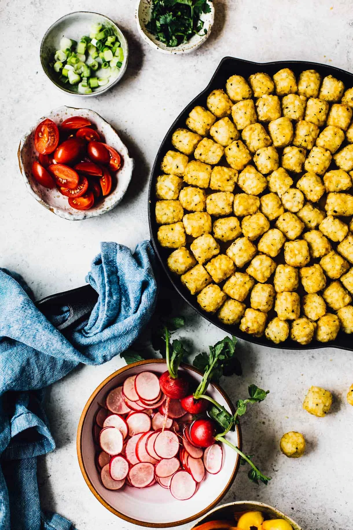 assembling a tater tot hotdish with bowls of fixings around it