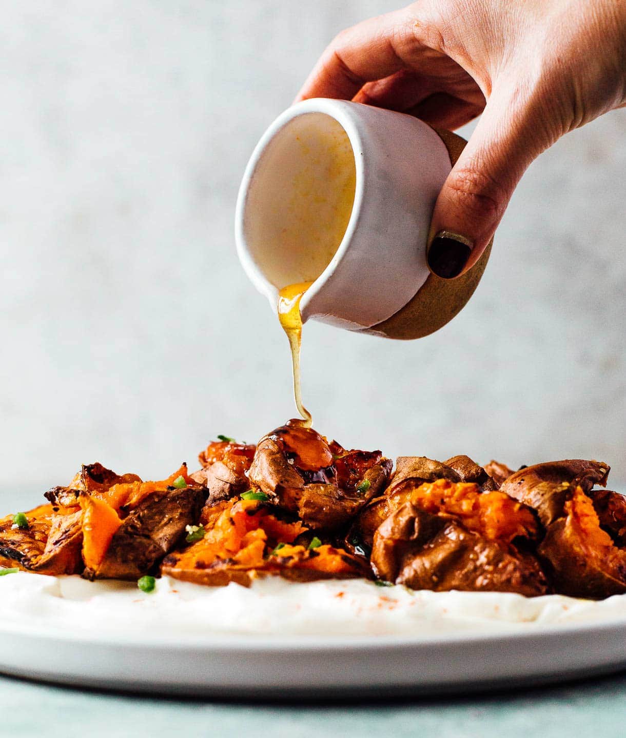 pouring hot honey on roasted sweet potatoes