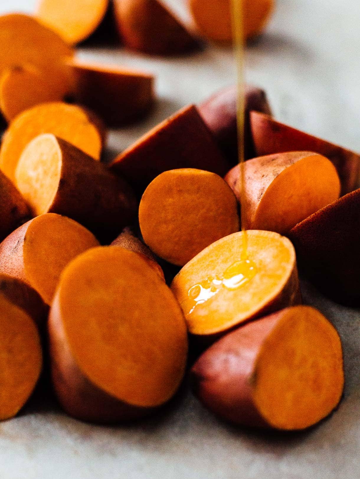 drizzling olive oil on sweet potato chunks