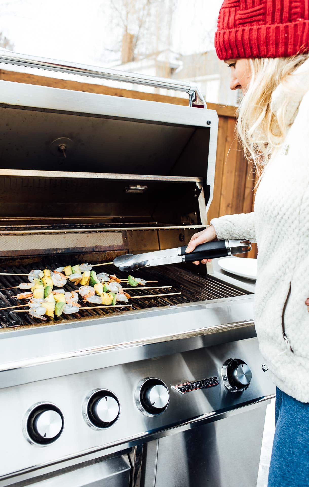 putting shrimp kabobs on the grill while grilling outdoors in winter