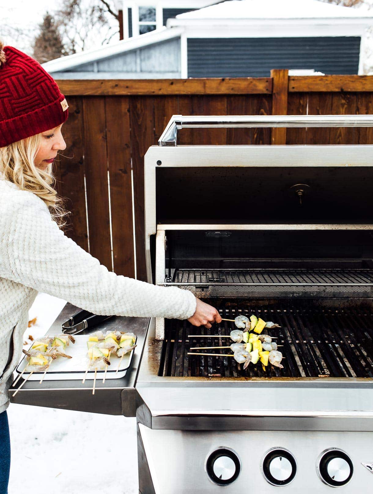 putting shrimp kabobs on the grill while grilling outdoors in winter