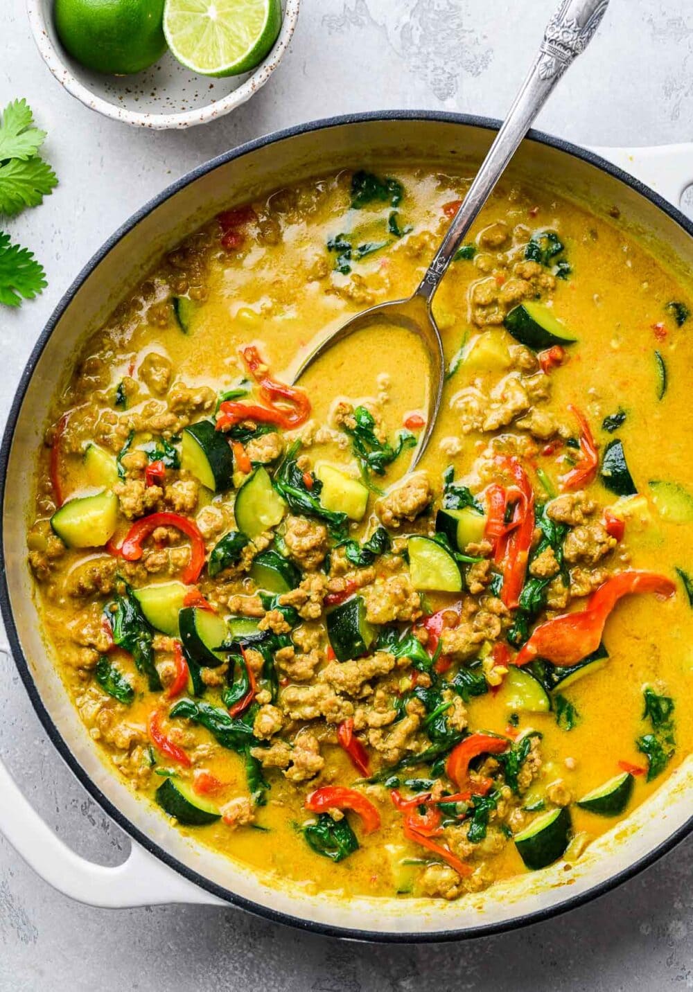 ground turkey curry braising in a pot, with a spoon