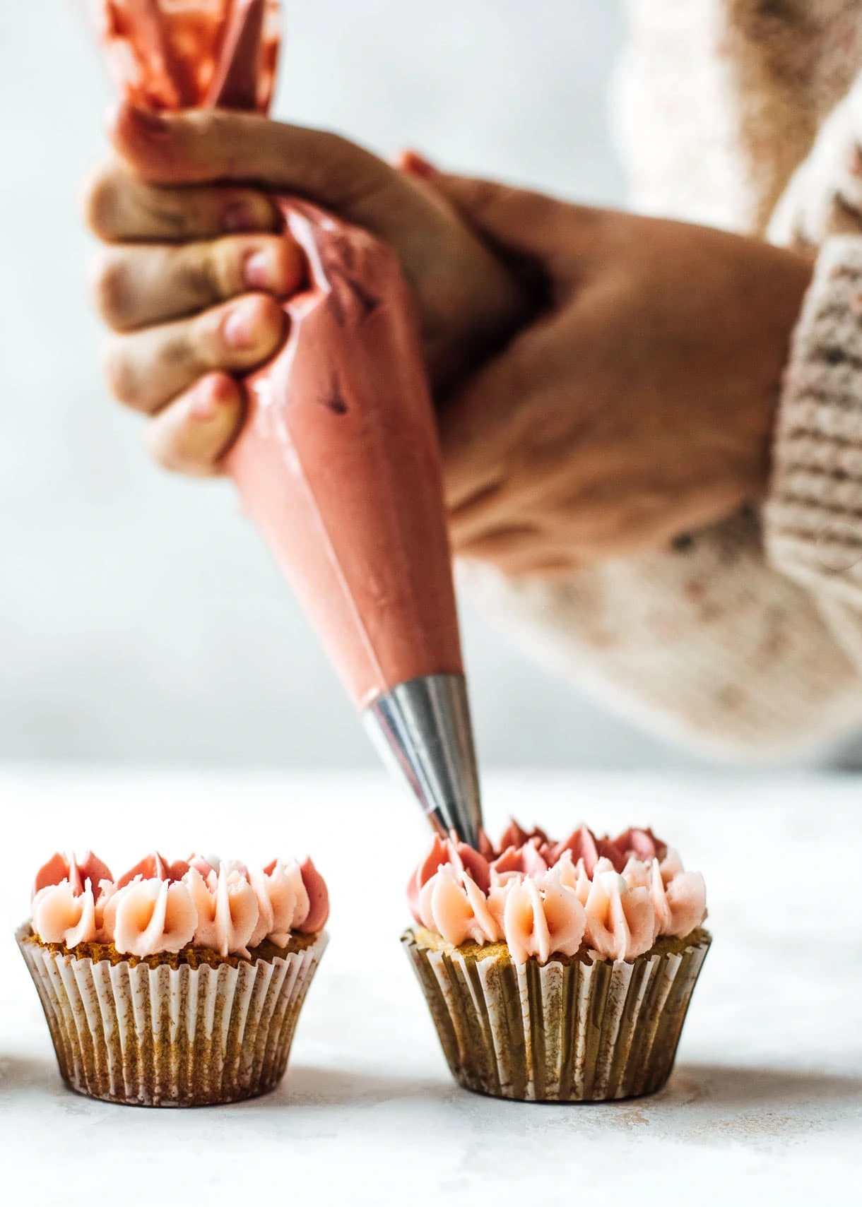 Piping pink frosting onto cupcakes using a #2 tip
