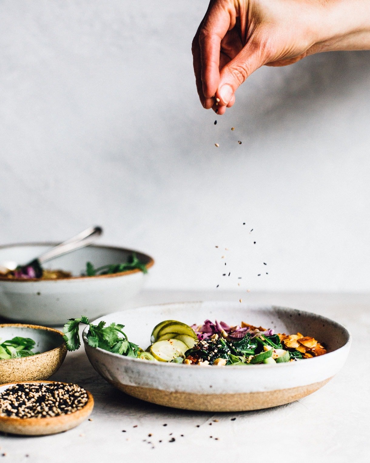 sprinkling sesame seeds over a bowl of congee