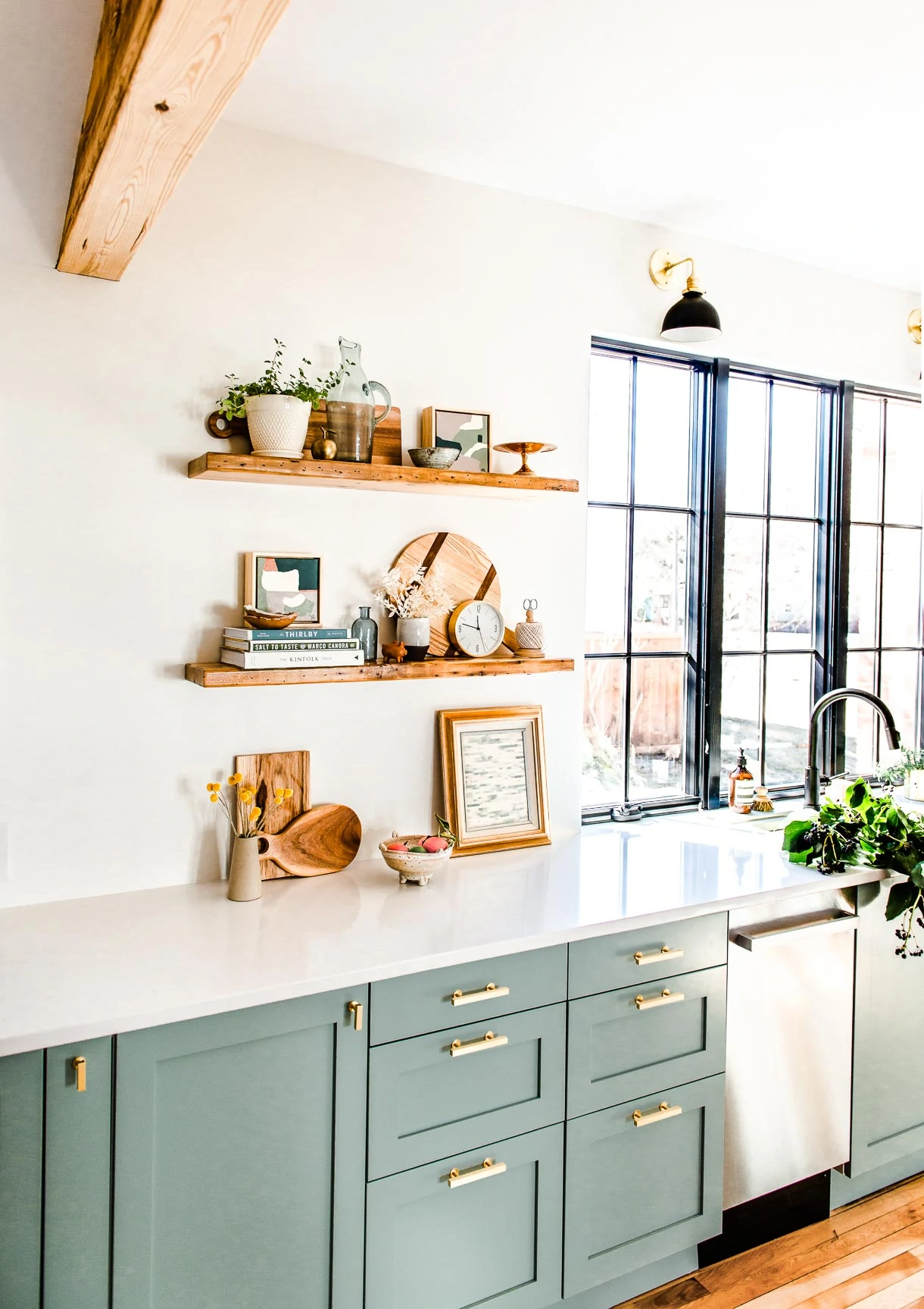 modern white kitchen with reclaimed wood shelves, flowers in sink, frameless window