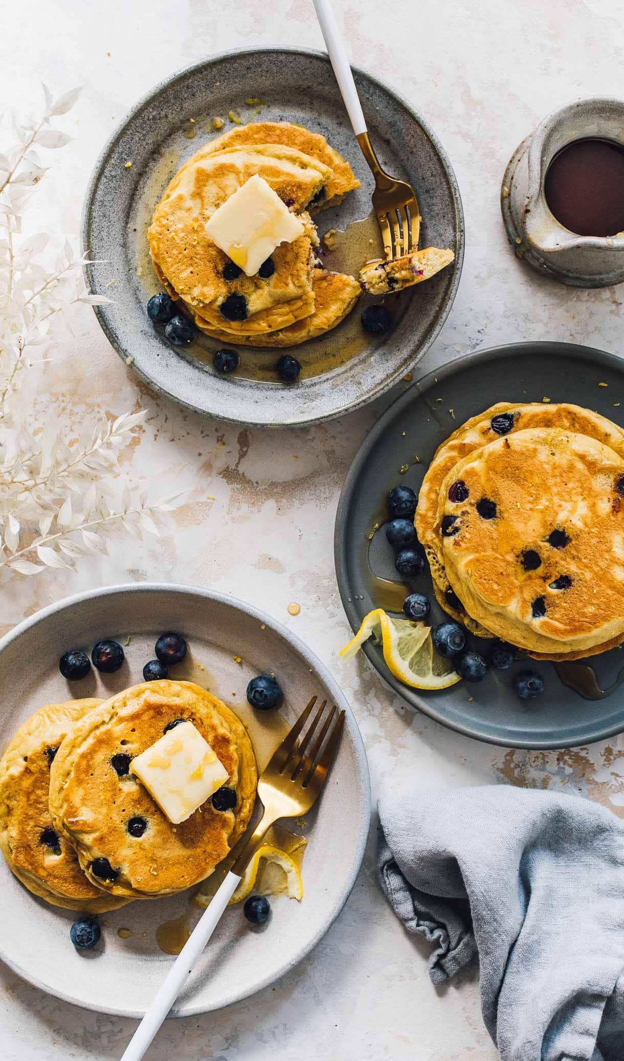 three plates of blueberry pancakes with maple syrup