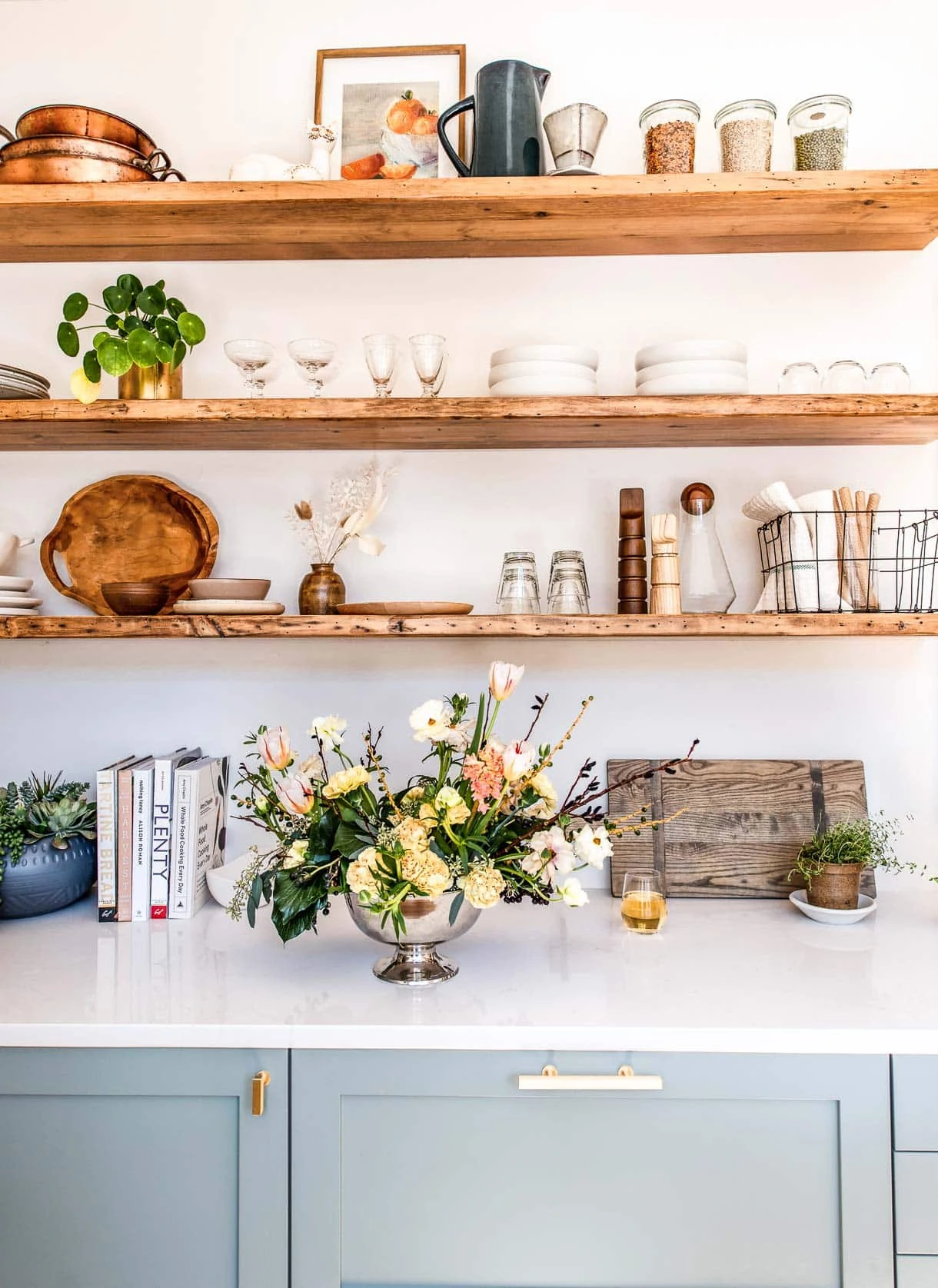open shelving with ceramics, glassware, and florals