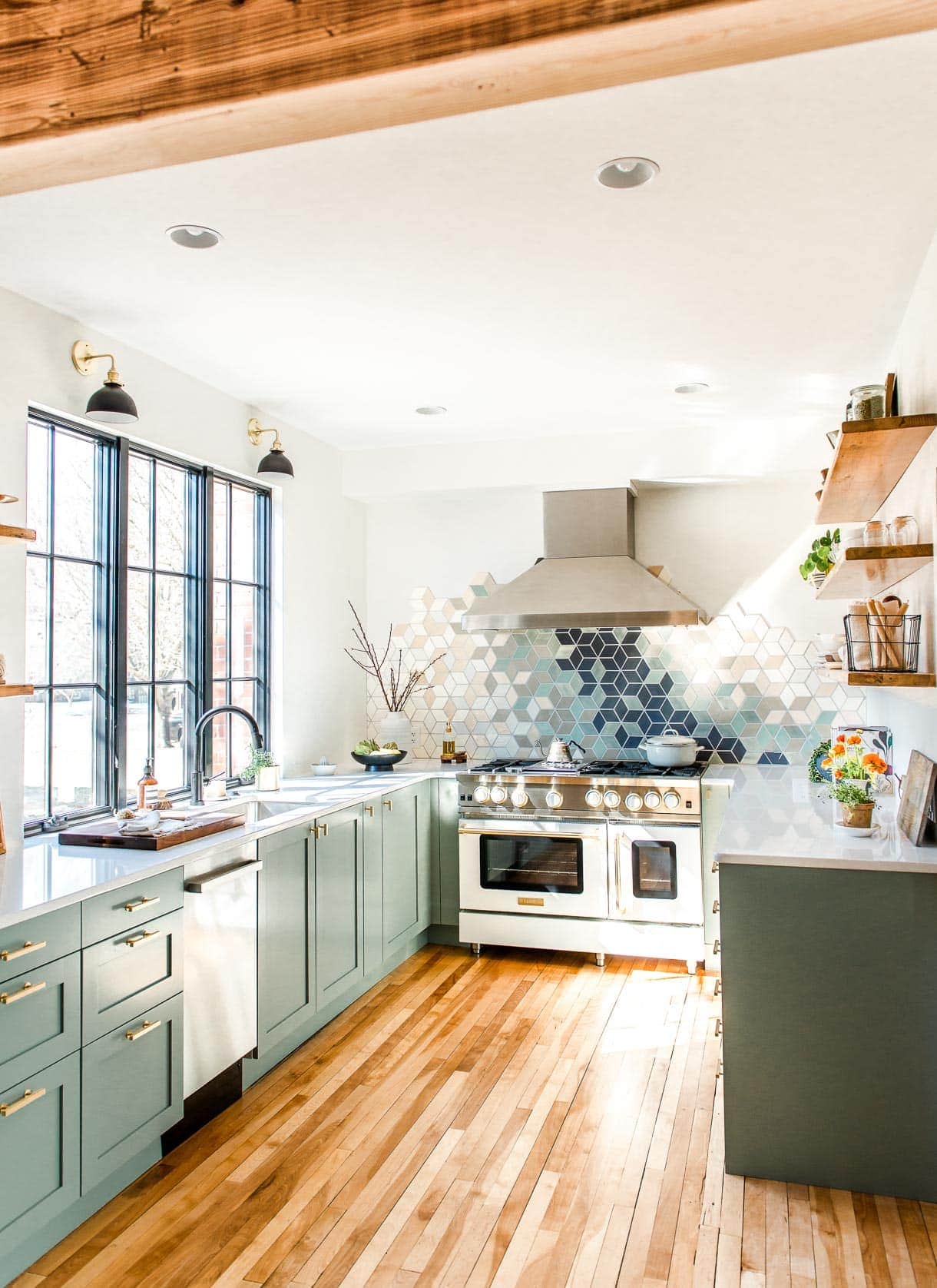 u shaped kitchen with sage green cabinets, frameless window and white range