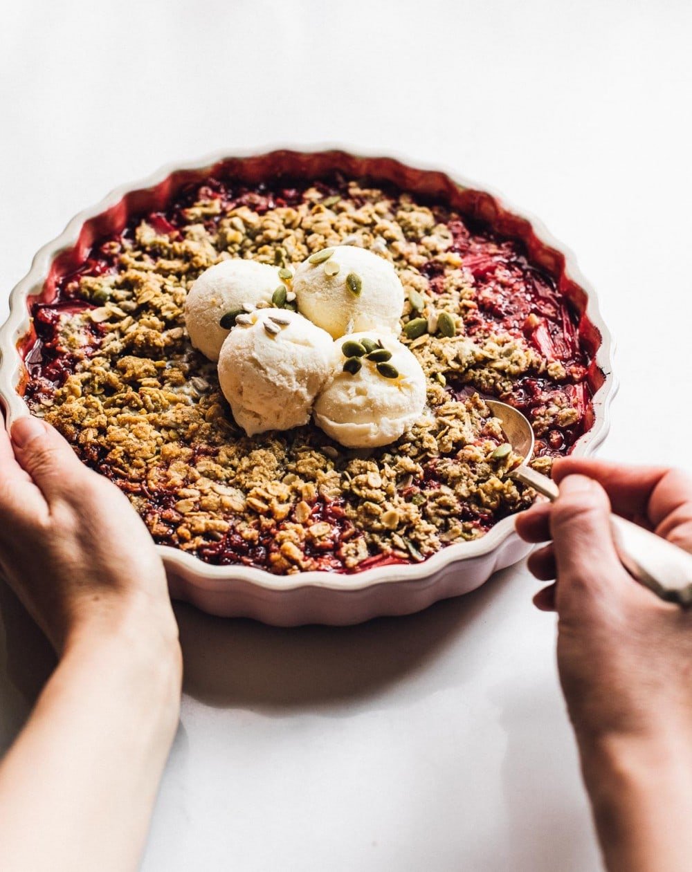 holding a pan of rhubarb crisp with vanilla ice cream