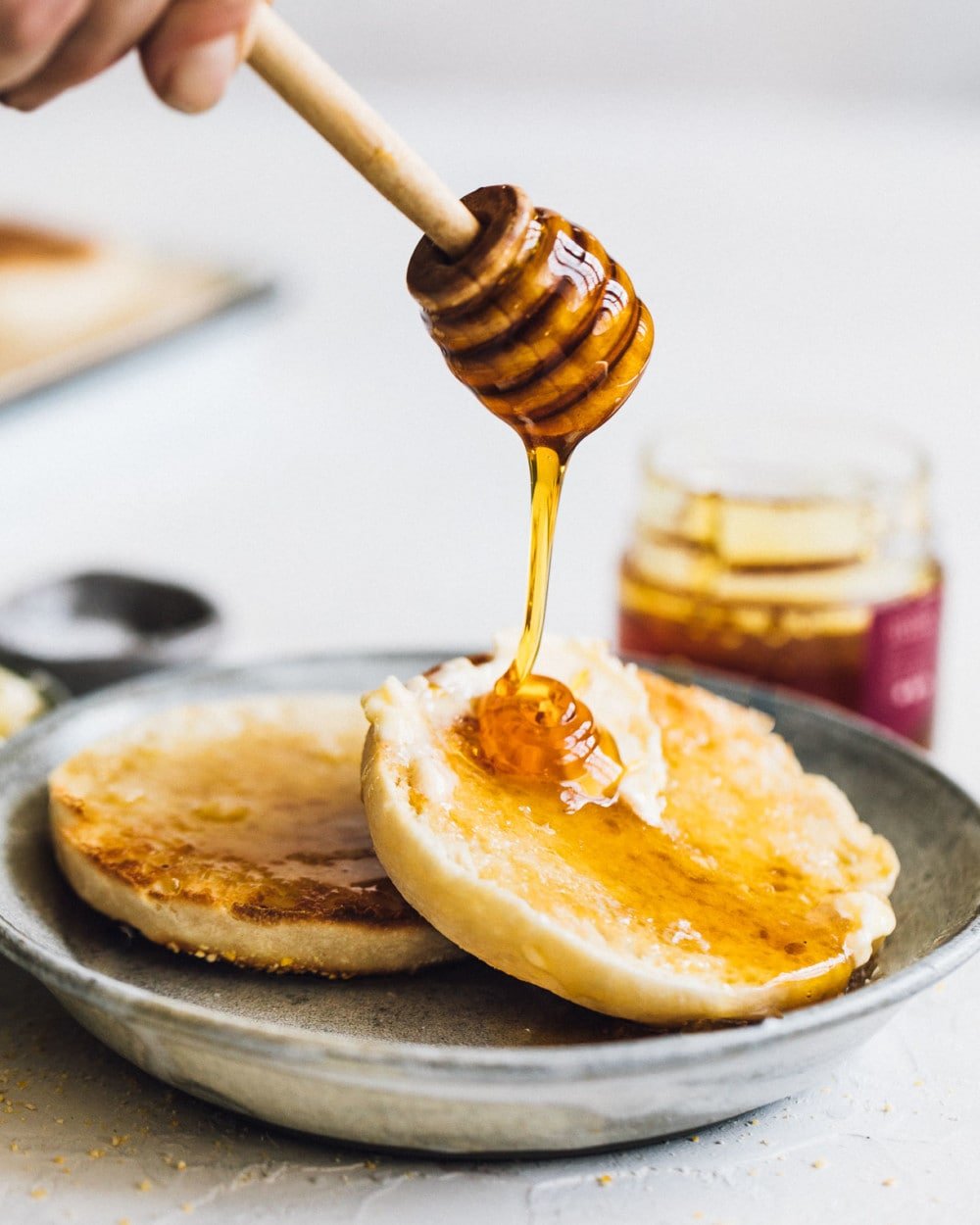 drizzling honey on homemade sourdough muffins