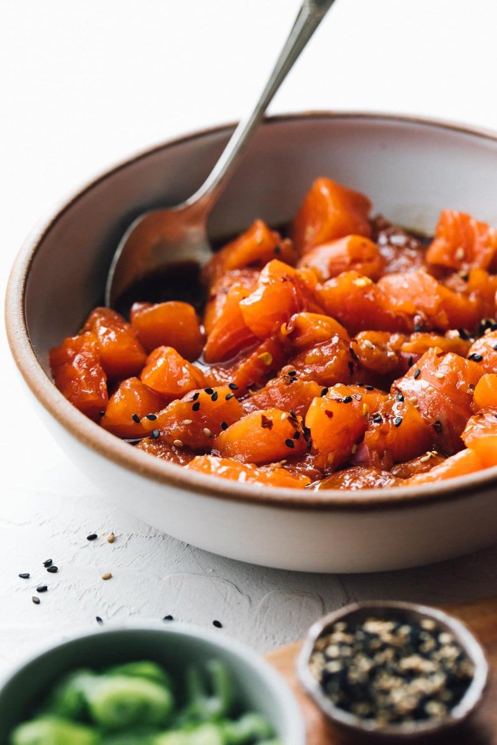 marinated salmon in a white bowl with spoon