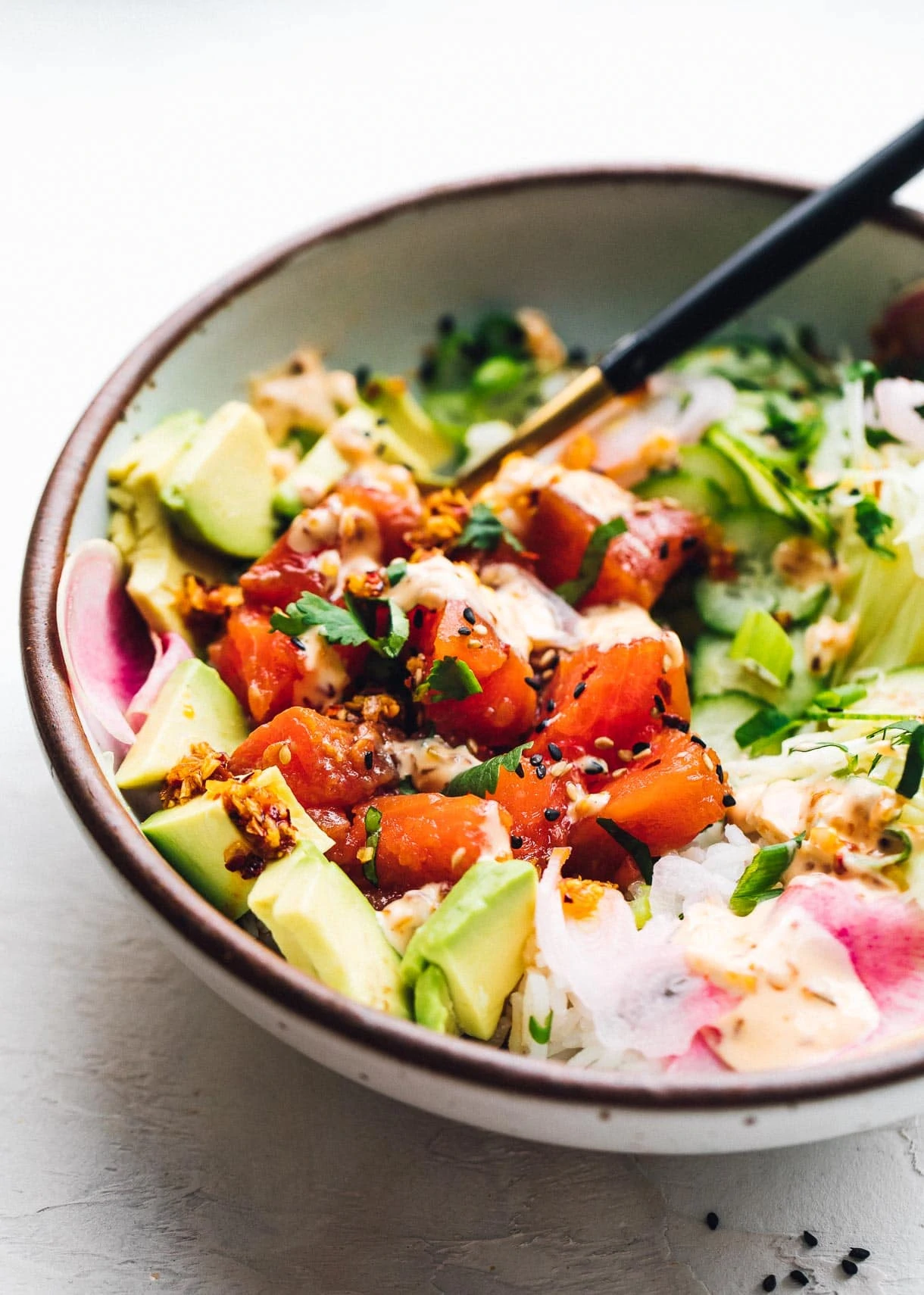 bowl of salmon poke with avocado in a bowl with a fork