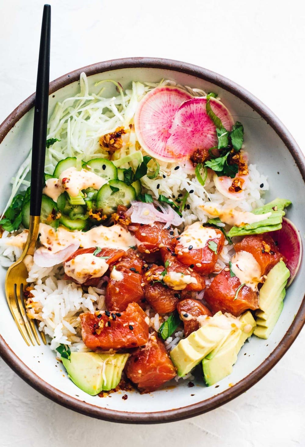 bowl of salmon poke with avocado in a bowl with a fork, overhead photo