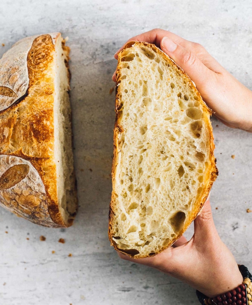 person holding loaf of bread sliced in half