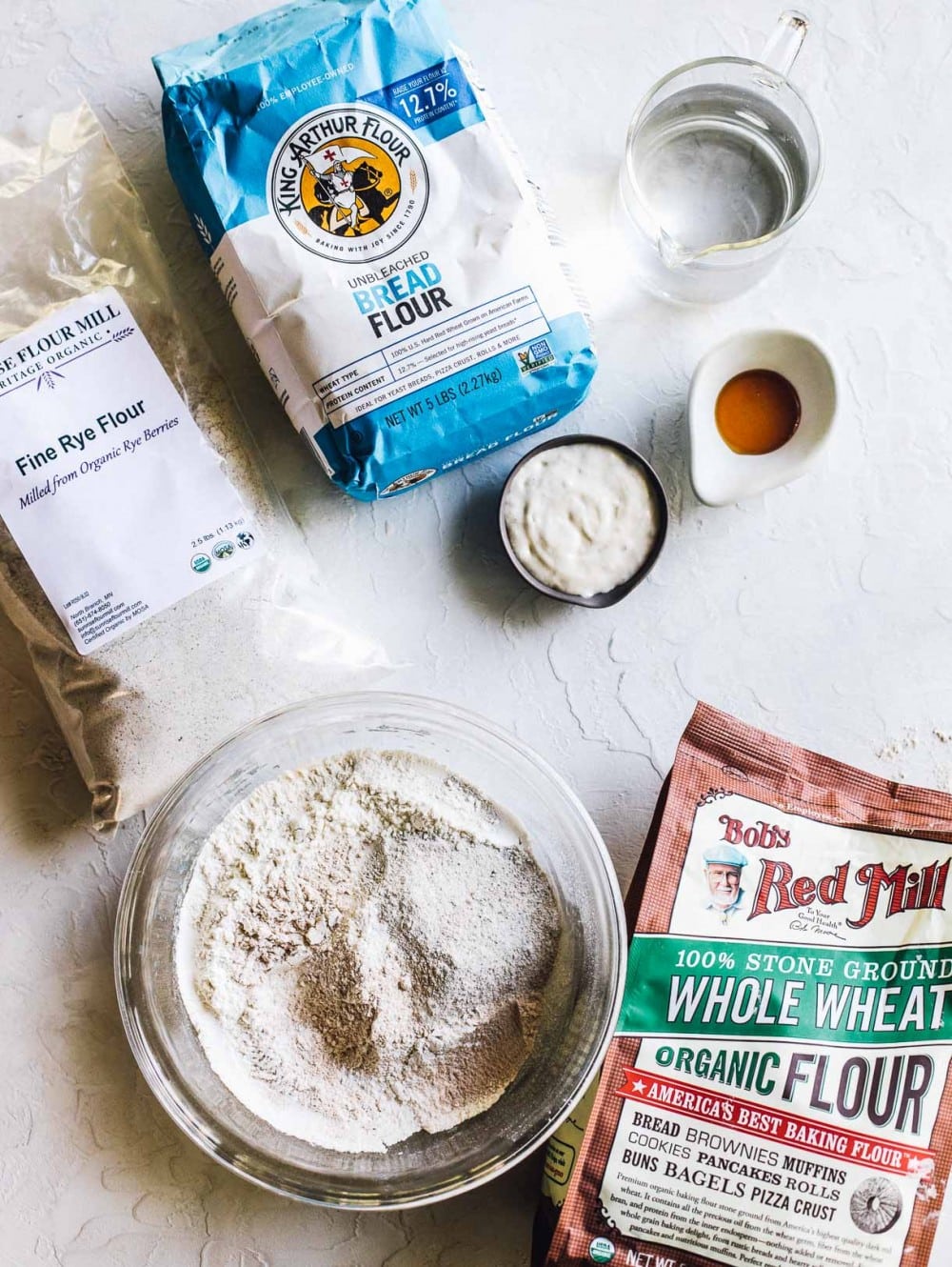 ingredients to make rye sourdough bread including bread flour, whole wheat flour in a bow, top down photo