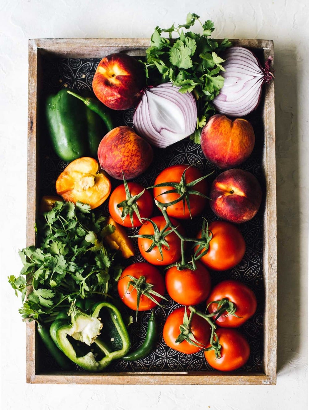 fresh tomatoes, cilantro, green pepper, onions, peaches on a tray, overhead photo