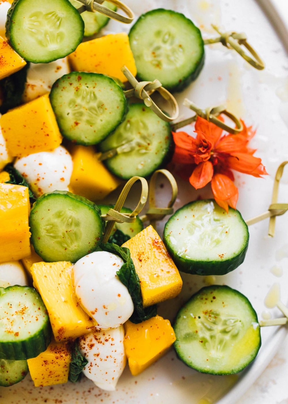 cucumber mango mozzarella skewers on a white plate