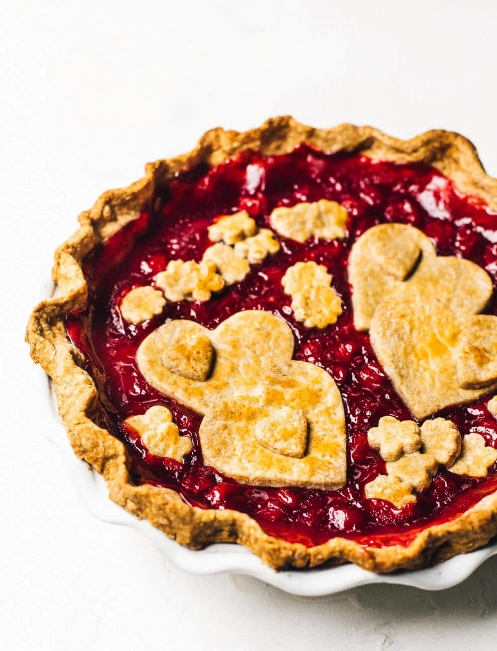 tart cherry pie in a white pie plate, with heart shapes on top cut from pastry