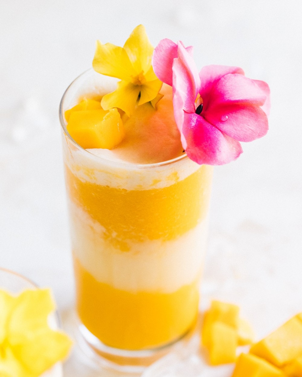 beautiful mango lava flow cocktail with pink and yellow flowers as garnish
