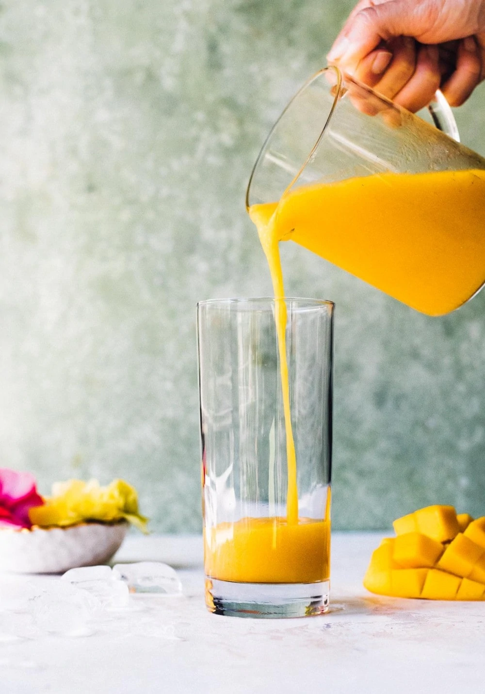 Pouring mango puree in a tall clear glass
