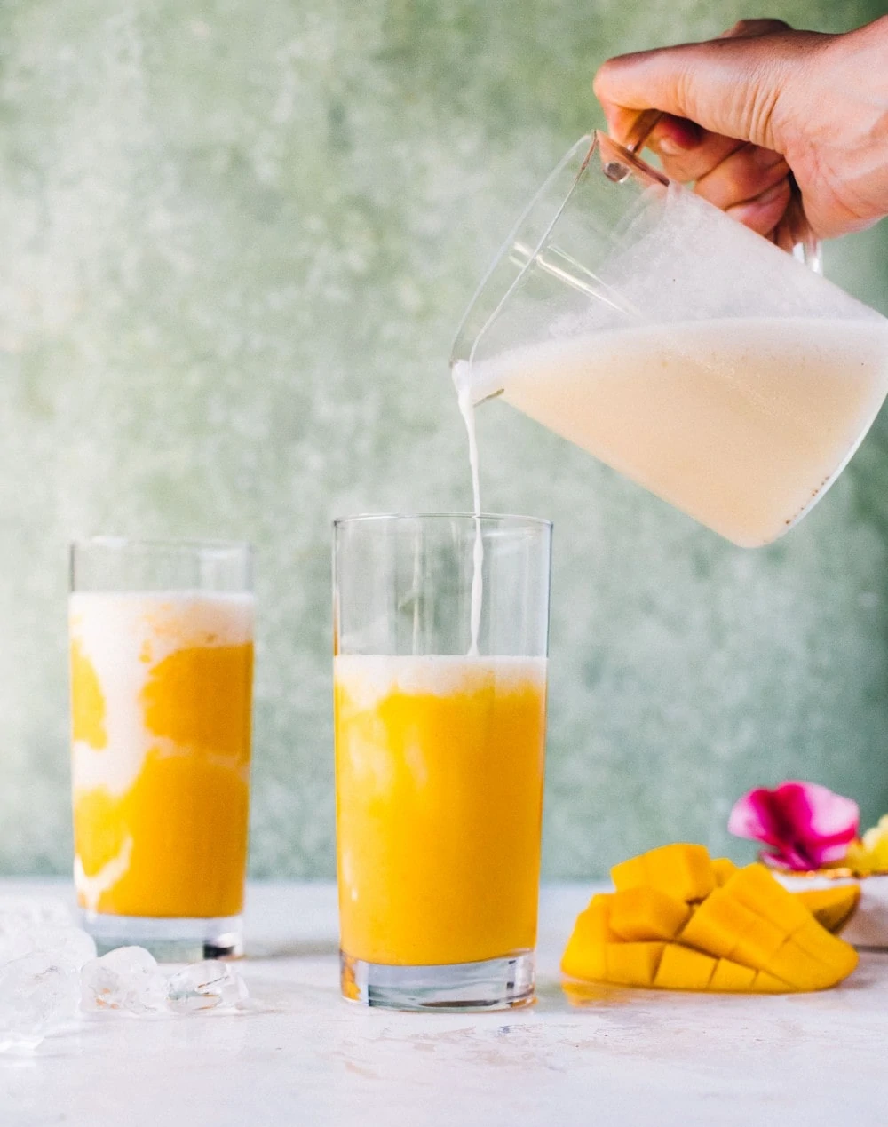 pouring coconut mixture into a mango cocktail