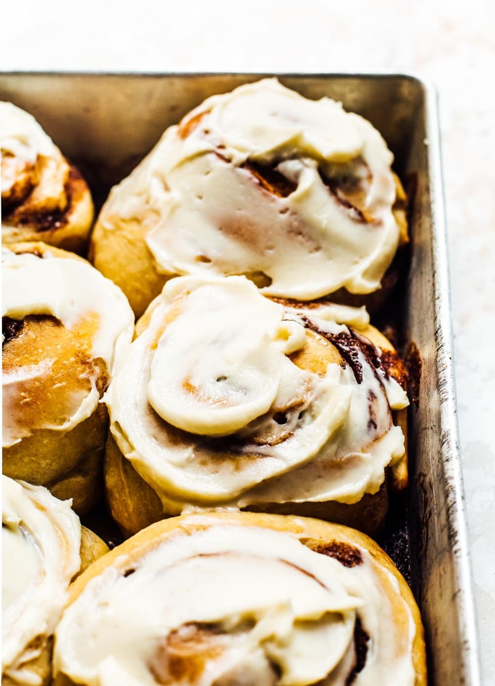 Sourdough Cinnamon Rolls, frosted with cream cheese frosting in an aluminum baking pan