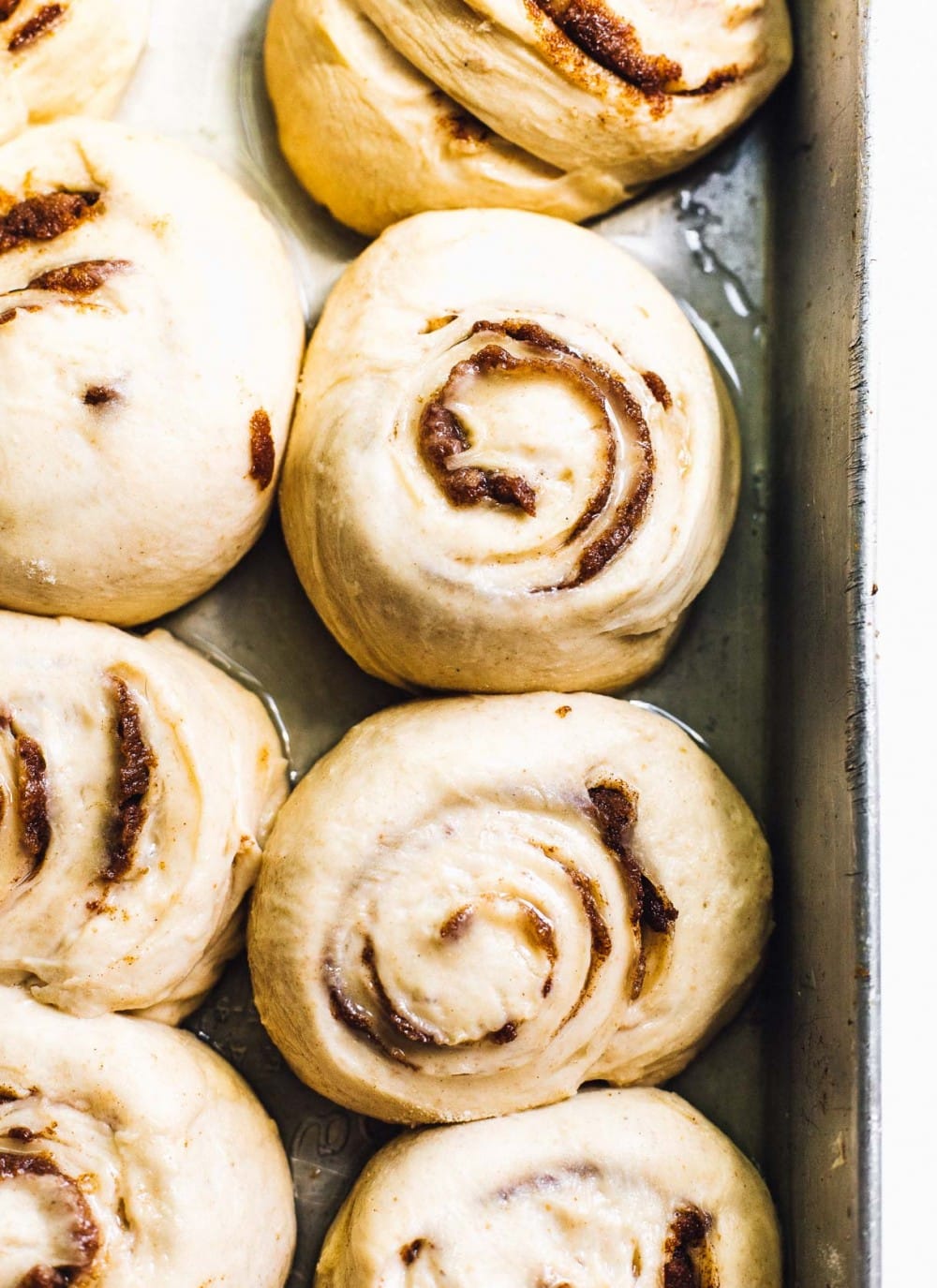 cinnamon roll dough rising in an aluminum pan