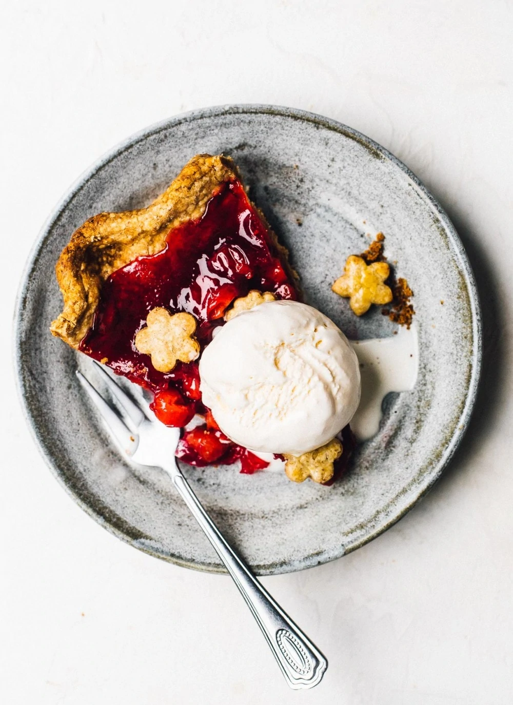 tart cherry pie on a plate with vanilla ice cream and a fork