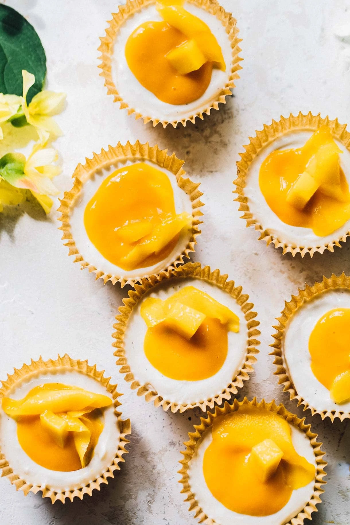 mango cheesecake bites scattered on a white surface, with fresh mango cheesecake topping