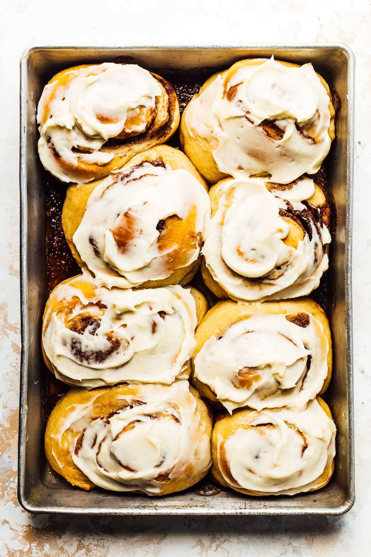 a pan of sourdough cinnamon rolls slathered with cream cheese frosting