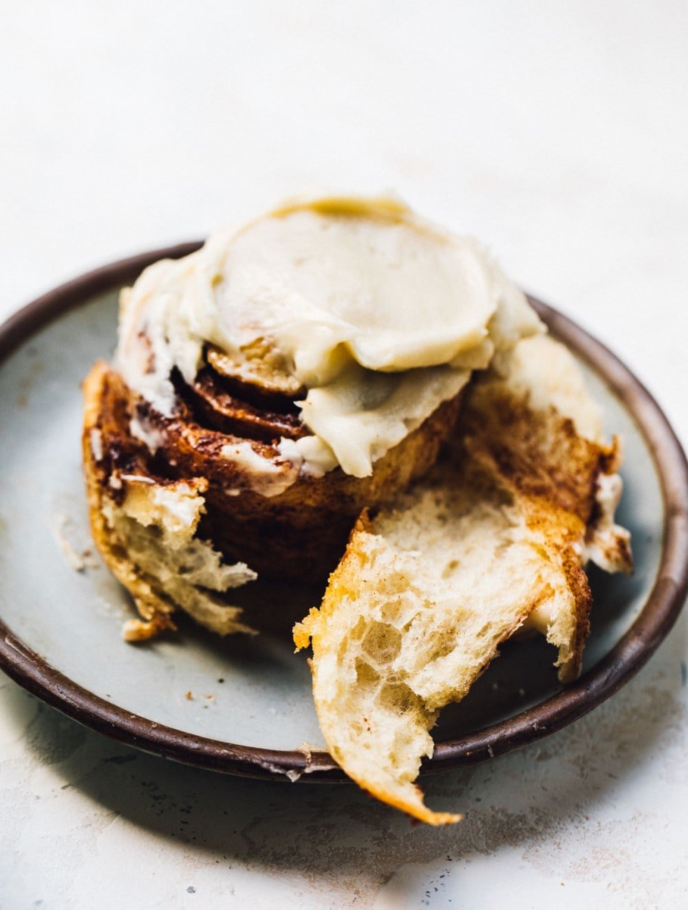 cinnamon roll with cream cheese frosting on a blue plate