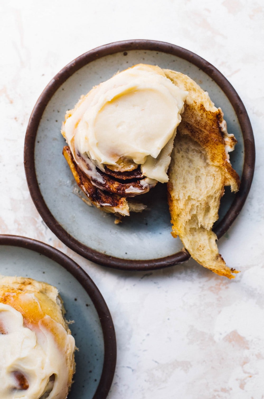 two sourdough cinnamon rolls, on two blue plates