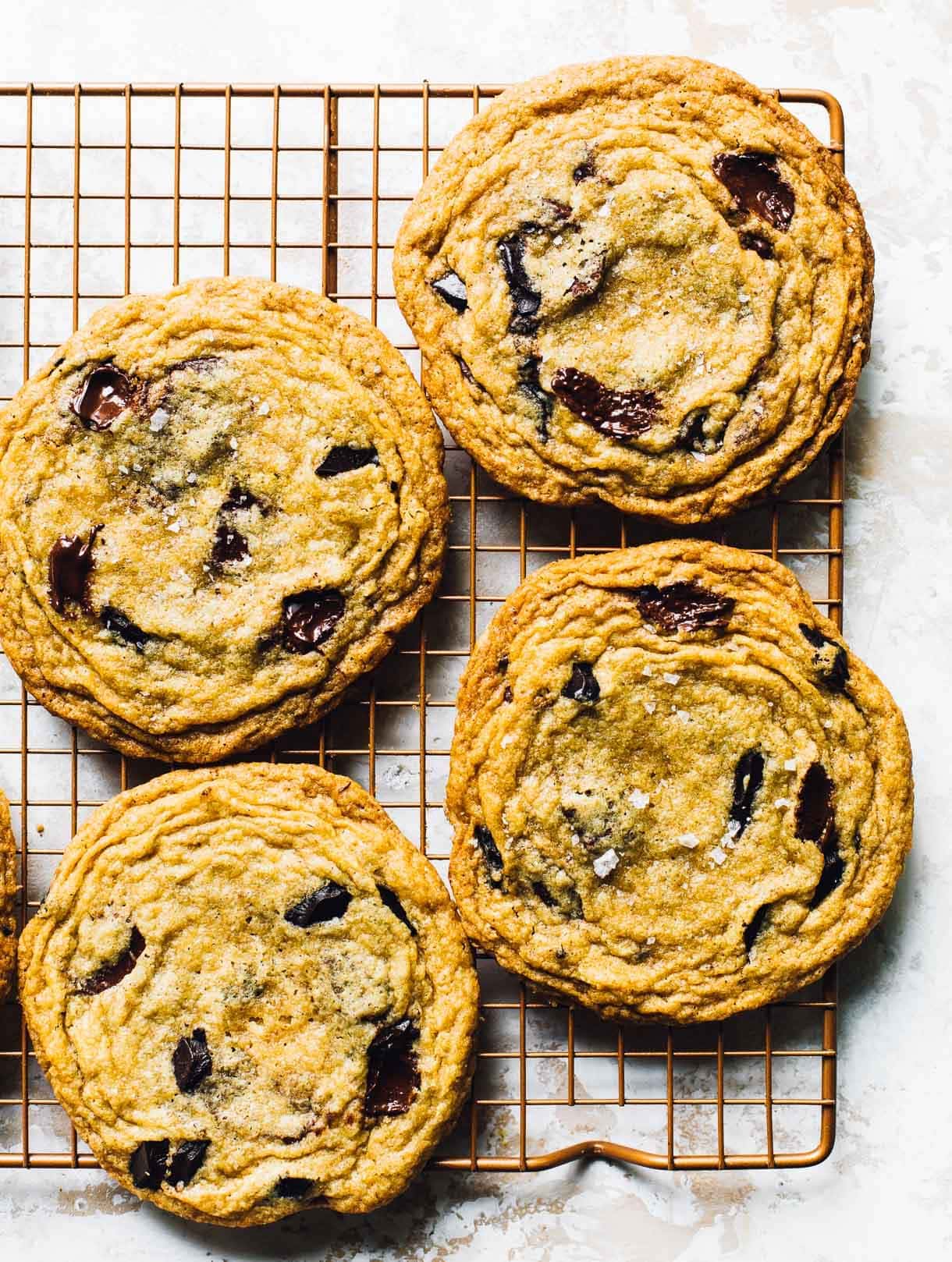 pan-banging chocolate chip cookies on a copper cooling rac