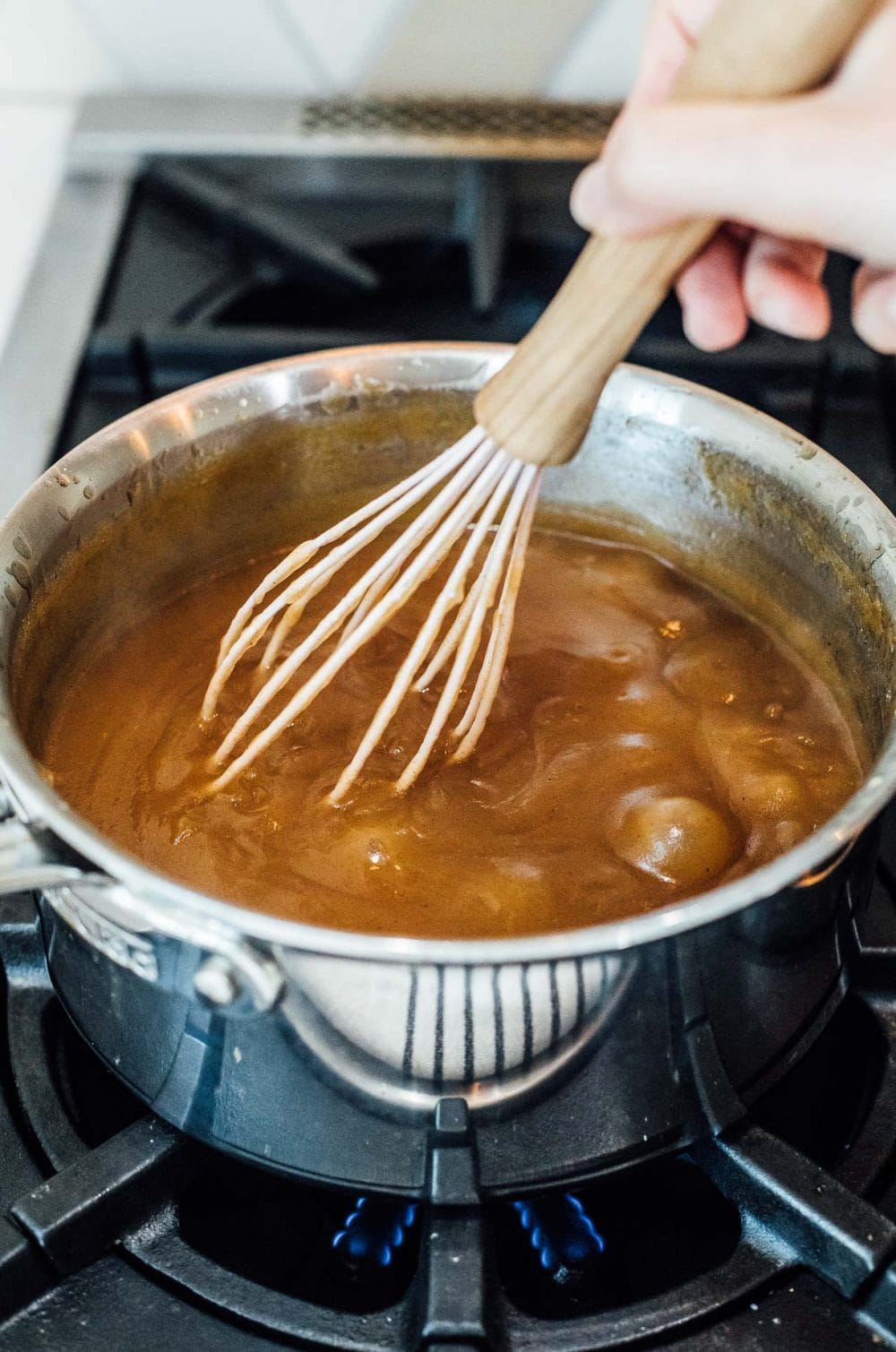 apple butter being stirred with a whisk in a saucepan