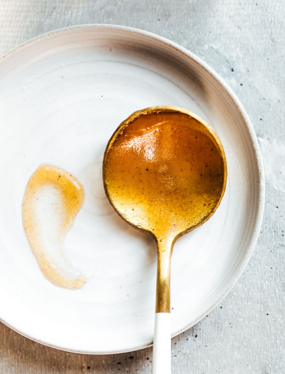 apple butter on a gold spoon, resting on a round spoon rest